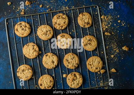 Gebackene Plätzchen auf einer blau strukturierten Oberfläche mit Keksbröseln Stockfoto