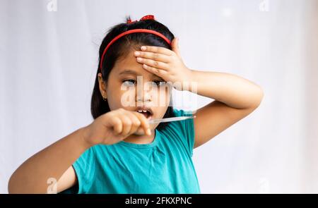 Selektiver Fokus auf ein indisches Mädchen mit analogem Thermometer in der Hand gehalten, Gesundheitskonzept Stockfoto