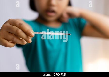 Selektiver Fokus auf ein analoges Thermometer, das in der Hand eines Kindes gehalten wird, Gesundheitskonzept Stockfoto