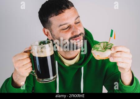 Ein Mann, der Donuts und Stout zum Frühstück isst, um St. Patricks Tag Stockfoto