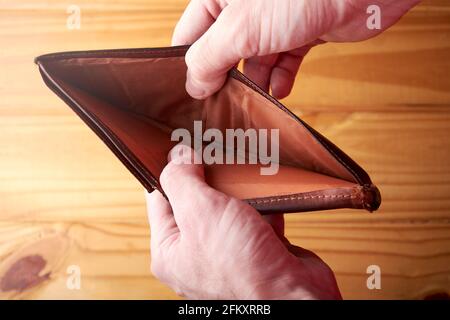 Hände eines armen kaukasischen jungen erwachsenen Mannes, der eine leere Brieftasche öffnet und nach Geld sucht. Konzept der Finanzkrise, Konkurs. Stockfoto