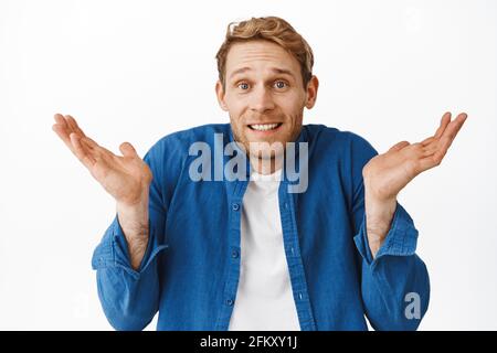 Es tut mir leid. Verwirrt Rotschopf Kerl zuckend und schauen ahnungslos, haben keine Ahnung, nicht verstehen, nichts, stehen unbewusst gegen weiß Stockfoto