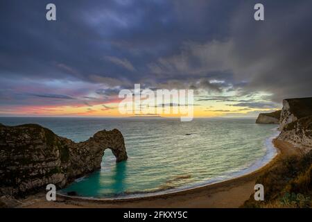 Sonnenuntergang hinter dem natürlichen Kalksteinbogen von Durdle Door an der Jurassic Coast von Dorset im südlichen Enland. Stockfoto