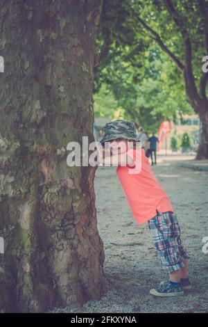 Junger Junge, der unter einem Baum spielt Stockfoto