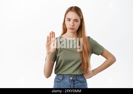 Halt, sie sagt nein Ernsthafte unzufrieden Frau, die erhöhte Handfläche zeigt, um etwas zu blockieren, abzulehnen, zu verbieten und abzulehnen, und vor weißem Hintergrund steht Stockfoto