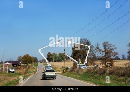 Zwei Linemen stehen in Kirschpflücker arbeiten an Telefonleitungen im ländlichen Arkansas. Das Auto hat sich verlangsamt, um die Ausrüstung zu umgehen. Stockfoto