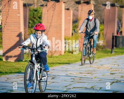 Bukarest, Rumänien - 03.13.2021: Vater und Sohn fahren an einem sonnigen Tag im Park von König Mihai I (Herestrau) in Bukarest mit dem Fahrrad Stockfoto