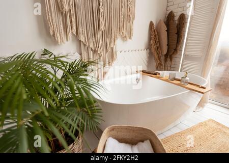 Gemütliches Badezimmer mit großer Badewanne, Pflanzen und rustikaler Dekoration Stockfoto