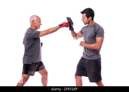 Älterer männlicher Athlet in hervorragender körperlicher Verfassung, in Boxhandschuhen, mit einem Fitnesstrainer, beim Boxen üben. Auf einem weißen, isolierten Hintergrund. Stockfoto