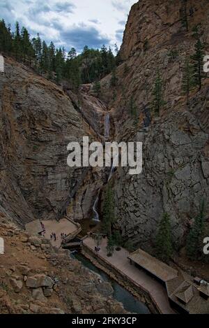 Touristen, die in Colorado Springs die sieben Stufen hinaufsteigen, um den Wasserfall zu sehen, der an den Bergklippen entlang zum Pool unter den Souvenirläden führt. Stockfoto