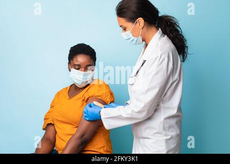 Arzt klebt Verband nach Impfstoffinjektion am Arm des Patienten, Studio Stockfoto