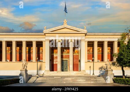 Athen, Attika, Griechenland. Das neoklassizistische Gebäude der Nationalen und Kapodistrianischen Universität von Athen. Blick auf die Fassade bei Sonnenuntergang mit bunt bewölktem Himmel Stockfoto