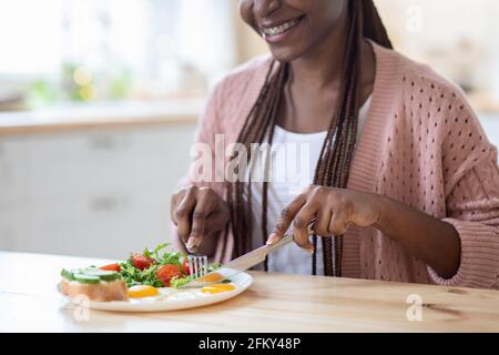 Abendessen Am Morgen. Beschnittenes Bild Einer Jungen Schwarzen Frau, Die In Der Küche Frühstück Isst Stockfoto