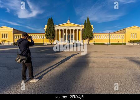 Athen, Attika, Griechenland. Junger männlicher Tourist fotografiert das berühmte neoklassizistische Gebäude Zappeion Hall im Zentrum von Athen Stockfoto