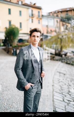 Groom steht auf dem Kopfsteinpflaster der Straße in Varenna vor dem Hintergrund alter Villen. Comer See Stockfoto