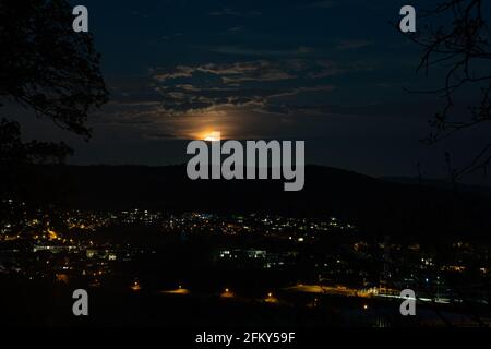 Aufsteigender Supermond mit Wolken über dem Stadtbild von Gebenstorf und Brugg, Kanton Aargau in der Schweiz. Magisches dunkles astronomisches Ereignis am 27. April 2021. Stockfoto