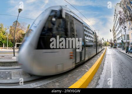 Die Straßenbahn der Stadt Athen fährt am Syntagma-Platz in Richtung Hauptbahnhof. Straßenbahn in Bewegung. Sonniger Tag mit blauem Himmel in Athen, Griechenland. Stockfoto