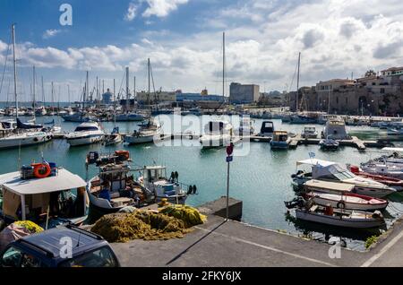 Heraklion, Kreta, Griechenland. Blick auf den alten venezianischen Hafen in Heraklion. Fischerboote und Yachten werden am Hafen angedockt. Tagsüber, wolkig Stockfoto