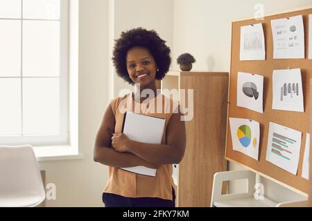 Porträt einer glücklichen jungen afroamerikanischen Frau, die im Büro und steht Lächelnd auf die Kamera Stockfoto