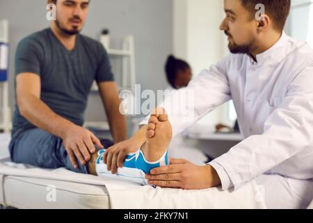 Der Arzt untersucht den Patienten mit gebrochenem Bein in orthopädischer Bandage Krankenhausbett Stockfoto