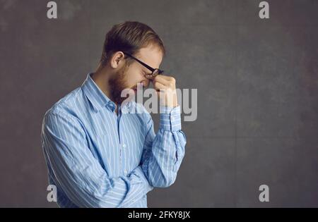 Müde junger Mann, der an Computer-Augenbelastung leidet, die ihn reibt Nach einem langen Arbeitstag Schmerzen in den Augen Stockfoto