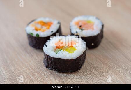 Drei Rollen Sushi auf einem Holzhintergrund Stockfoto