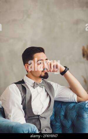 Bräutigam im Anzug und Fliege auf einem Stuhl Stockfoto