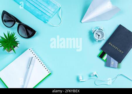 Sicheres Reisekonzept während der Coronavirus-Pandemie. Reisepass, medizinische Maske und Sonnenbrille auf blauem Hintergrund. Flatlay, Bannerformat. Stockfoto