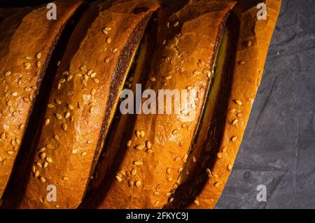 Ungewöhnlicher zweifarbiger frischer Laib Brot auf schwarzem Hintergrund, Foto in einer niedrigen Taste bei hartem Licht, Nahaufnahme Stockfoto