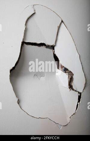Gebrochene Gipskartonwand mit einem großen Riss darauf. Stockfoto