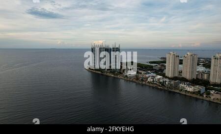 Das Stadtbild der indonesischen Stadt Jakarta mit Blick auf das Meer, den Hafen, die Palmen und die Apartments spiegeln sich auf der Wasseroberfläche. Jakarta, Indonesien, Mai 5, Stockfoto