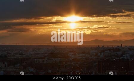 Panorama der Stadt unter dem goldenen Licht der Untergehende Sonne aus einer Höhe, in der die Gebäude gesehen Und der Himmel bedeckt von einem dichten schwarzen Klo Stockfoto