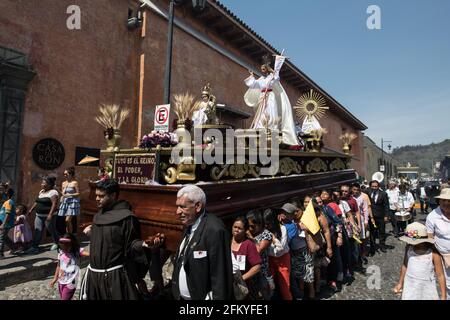 Frauen tragen während der Semana Santa Prozession in Antigua, Guatemala, einen kunstvollen hölzernen Wagen (anda), eine bunte Demonstration von Glauben und Tradition. Stockfoto