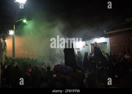 Nachts nimmt die Semana Santa-Prozession in Antigua eine geheimnisvolle, spirituelle Atmosphäre an, während Räucherrauch die Luft um eine beleuchtete Ananda füllt. Stockfoto