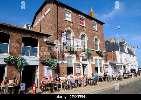 Leute, die draußen sitzen und in der Sommersonne Drinks im George Bar & Grill genießen, einem Pub am Kai in Weymouth, Dorset, England, Großbritannien Stockfoto