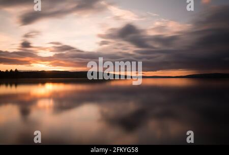 Wunderschöner Sonnenuntergang über einem schwedischen Natursee, fotografiert mit Long Belichtung Stockfoto