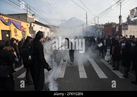 Weihrauch füllt die Straßen, während die Menschen während der Karwoche an einer Semana Santa Prozession in Antigua, Guatemala, einer historischen Kolonialstadt, teilnehmen. Stockfoto