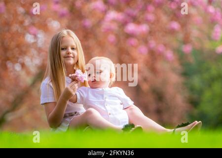 Junges Mädchen mit ihrem kleinen Bruder draußen auf der Gras Stockfoto