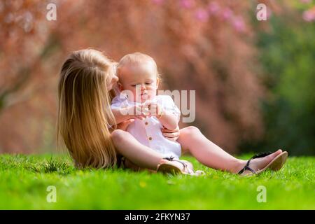 Junges Mädchen mit ihrem kleinen Bruder draußen auf der Gras Stockfoto