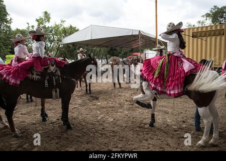 Die Escaramuzas zeigen ihre bemerkenswerten Sidesaddle-Fähigkeiten und ihre traditionelle Kleidung im Campeonato Millonario Lienzo de Charro in Jalisco, Mexiko Stockfoto