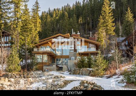 REVELSTOKE, KANADA - 16. MÄRZ 2021: Berghaus aus Holz im Wald zwischen hohen Bäumen. Stockfoto