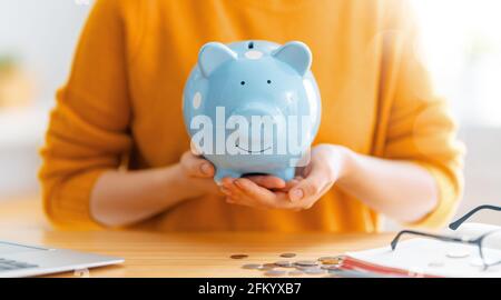 Frau sitzt am Schreibtisch mit Sparschwein. Konzept der Verwaltung des Familienbudgets. Stockfoto