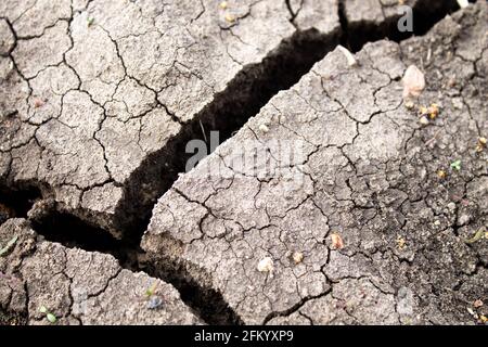 Tiefe Risse im Boden. Der trockene Boden rissig. Schwarzer Boden mit tiefen Spaltungen. Die Folgen eines Erdbebens. Stockfoto