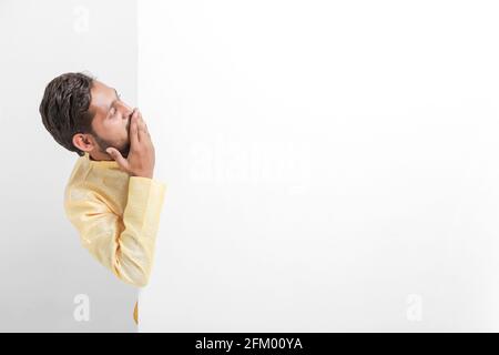 Ein indischer Mann mit Whiteboard, der während der Festivalsaison Angebote propagiert, während er traditionelle Tücher trägt und auf weißem Hintergrund steht. Stockfoto