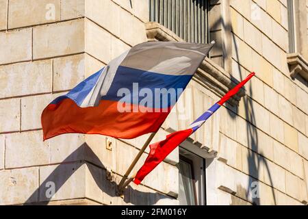 Russische Flaggen aus nächster Nähe an der Fassade des Gebäudes. Sewastopol, Krim, 13. August 2020. Das Staatssymbol Russlands entwickelt sich im Wind. Stockfoto