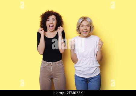 Überrascht lächeln die lockigen Frauen in einem gelben Studio Wand, die Glück gestikuliert Stockfoto