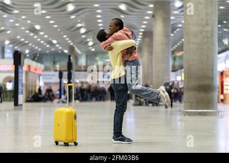 Liebevolles Paar glückliches Treffen nach langer Zeit. Afrikanischer Mann und Frau freuten sich über die Umarmung im Flughafenterminal Stockfoto