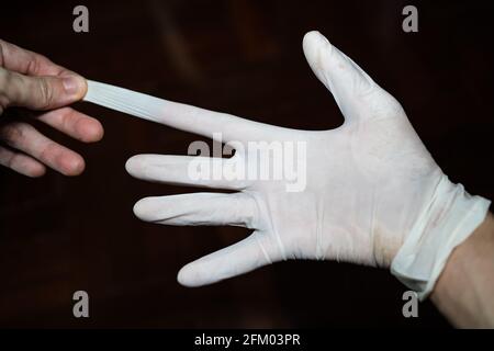 Den Latexhandschuh auf der rechten Hand strecken Stockfoto