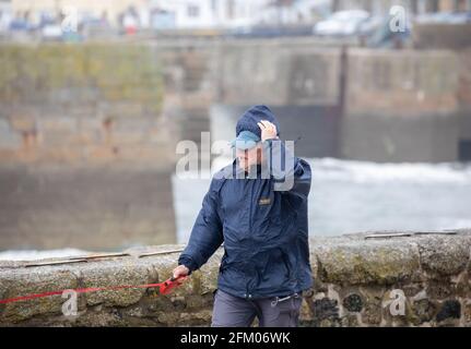Die Menschen kämpfen gegen die starken Winde in Porthleven, Cornwall, Großbritannien Stockfoto