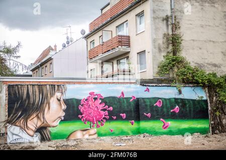 Ein Graffiti an einer alten Mauer zeigt ein Mädchen, welches wie bei einer Pusteblume ein Coronavirus anpustet, welches dann auseinander fliegt. Ein s Stockfoto